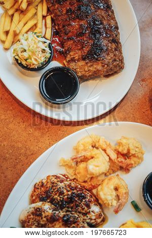 Close up Gourmet Grilled Pork Rib and Fried Potato Wedges on wood Plate with Sauce and Roasted chicken breast and mashed potatoes