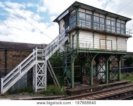 old british railway signal box with wooden white planks on an iron frame with white steps and track visible in the foreground taken in Canterbury kent