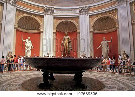 VATICAN, ROME, ITALY - JULY 15, 2017: Tourists and Hercules sculpture roman statues and round monolithic porphyry basin in Round Room of Pio-Clementino Museum in Vatican museums Vatican city Rome Italy
