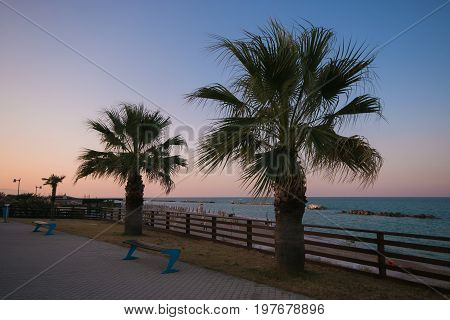 Bench on the seafront at sunset in Italy