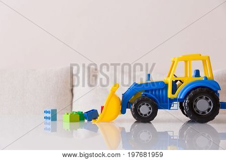 Closeup of children toy tractor with colorful plastic bricks or details on white background. Baby's toys on the table isolated.