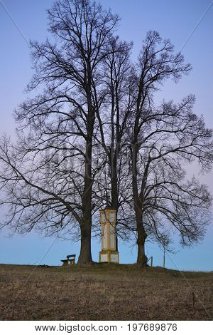 Three trees and calvary chapel with a bench in nature vertical natural photo