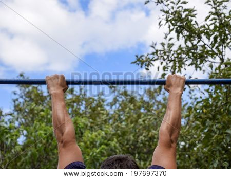Hands On The Bar Close-up. The Man Pulls Himself Up On The Bar. Playing Sports In The Fresh Air. Hor