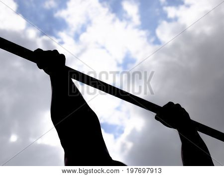 Silhouette Of Hands On A Horizontal Bar. Hands On The Bar Close-up. The Man Pulls Himself Up On The