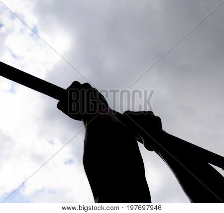 Silhouette Of Hands On A Horizontal Bar. Hands On The Bar Close-up. The Man Pulls Himself Up On The