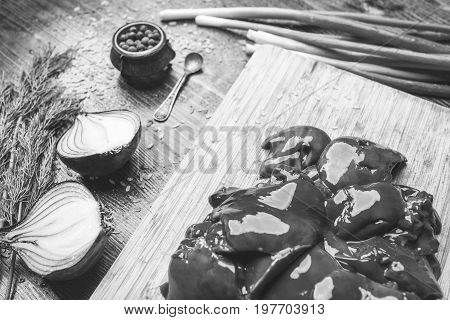 Fresh chicken liver onion dill black pepper on a wooden background black and white frame