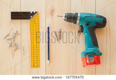 Electric screwdriver, roulette and handsaw at wooden desk background