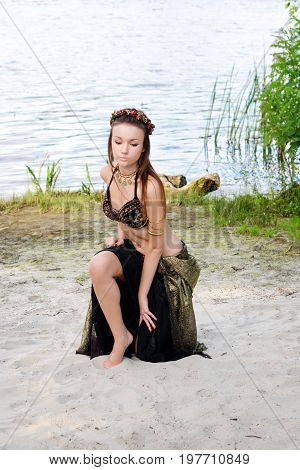 Young woman tribal american style dancer. Girl dancing and posing on the beach sand wearing belly dance costume. Ethnic dance. Belly dancing. Tribal dancing