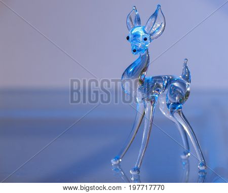 Closeup of a Figurine of a deer made of glass illuminated with blue light