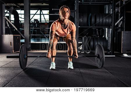 Muscular young fitness woman doing heavy deadlift exercise in gym