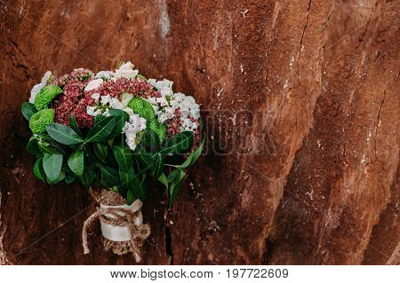 Rustic wedding bouquet with different flowers and greens on wooden background. Top view.