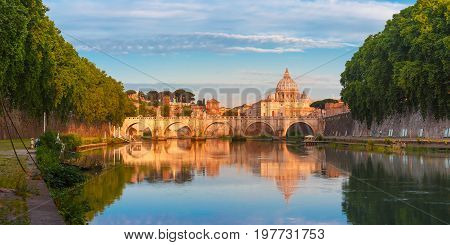 Panorama of Saint Angel bridge and Saint Peter Cathedral with a mirror reflection in the Tiber River in the sunny morning in Rome, Italy.