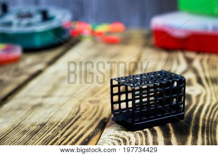 feeder ror fishing at the wooden table with fishing acsessories background