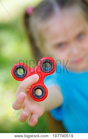 Little girl playing with red fidget spinner toy