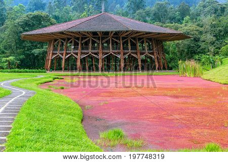 Large wooden building next a to lake covered in red plants near Manizales Colombia