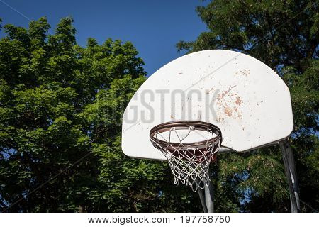 Old basketball hoop at a park with a blue sky background