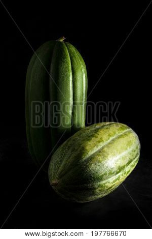 Two carosello cucumbers on black background. Carosello is a variety of cucumber mixed with melon cultivated in Apulia