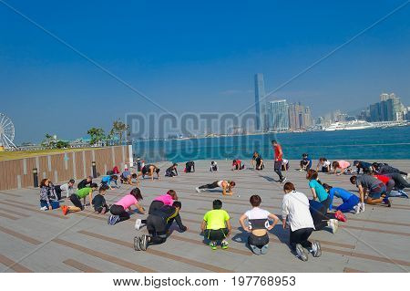 HONG KONG, CHINA - JANUARY 26, 2017: Crowd of people doing Tai Chi Exercising in the morning, with a downton of the city of Hong Kong as background. With a land of 1, 104 km and population of 7 million, Hong Kong is one of most densely populated areas in 