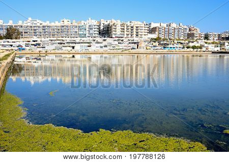 BUGIBBA, MALTA - MARCH 31, 2017 - View of salt pans with buildings to the rear in Salina Bay Bugibba Malta Europe, March 31, 2017.