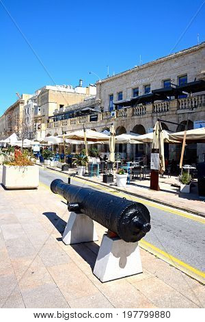 VITTORIOSA, MALTA - MARCH 31, 2017 - Cannon along the waterfront with pavement cafes to the rear Vittoriosa (Birgu) Malta Europe, March 31, 2017.