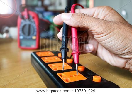 Electricians worker use voltmeter measure the current from extension cord sets plug.