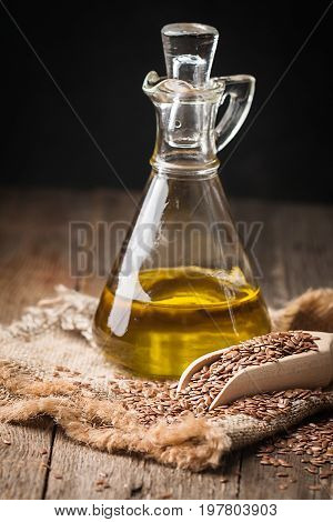 flax seeds and linseed oil in a glass jug on a wooden table, healthy diet with omega 3 fatty acids