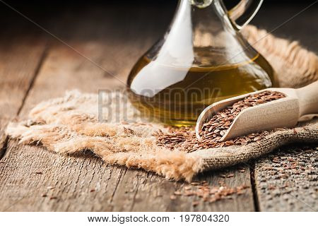 flax seeds and linseed oil in a glass jug on a wooden table, healthy diet with omega 3 fatty acids