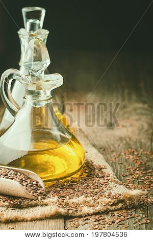 flax seeds and linseed oil in a glass jug on a wooden table, healthy diet with omega 3 fatty acids