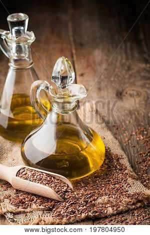 flax seeds and linseed oil in a glass jug on a wooden table, healthy diet with omega 3 fatty acids