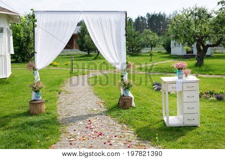 Arch for the wedding ceremony, decorated with cloth flowers and greenery