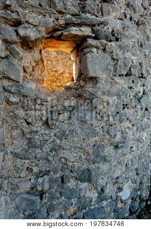 Abstract of the sun shining through a hole in a stone wall near the city of Cres (Croatia)
