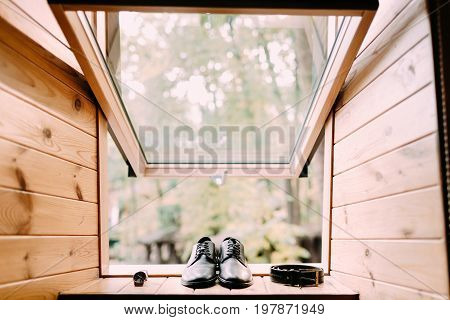 Groom's shoes leather belt and watch on light wooden windowsill background. Men's set. Preparation for wedding concept.