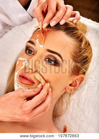 Collagen face mask. Facial skin treatment. Woman receiving cosmetic procedure in beauty salon. Bottle with moisturizing cream on background. Cropped shot of removing wrinkles Mask against sagging skin