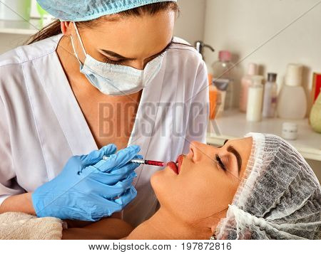 Filler injection for female forehead face. Plastic aesthetic facial surgery in beauty clinic. Silicone lips in the girl. Cosmetics in bottles in the background.