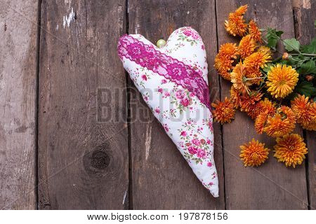 Fresh orange autumnal flowers chrisanthemum and heart on vintage wooden background. Selective focus. Place for text.