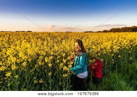 Teenage girl with long hair in yellow bittercress field sunset time