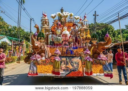 CHIANGMAI THAILAND - JANUARY 25 2015: Indigenous women and man with traitional costume sitting on decorated vehicle with flowers and bamboo hat fake elephants and chicken in parade of 22nd Traditional Skirt Fabric and The Indigenous Product and Culture Fe
