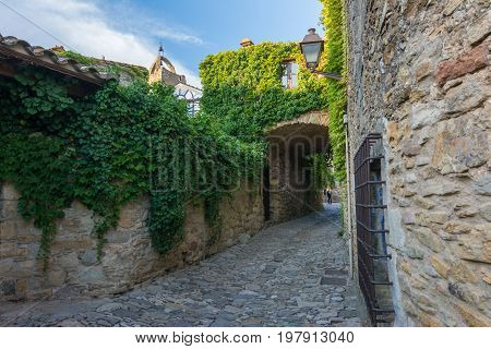 Narrow street and flowered facade in Peratallada. Peratallada is a picturesque medieval old town in the heart of Costa Brava, Catalonia, Spain.