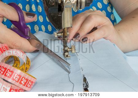 Woman hand on sewing machine.Dressmaker work on the sewing machine. Hobby sewing fabric as a small business concept. sewing machine and female scissors