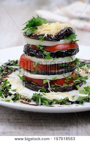 Appetizer from eggplant slices of mozzarella combined in a pile with tomatoes spilled with herbs seasoned Parmesan cheese