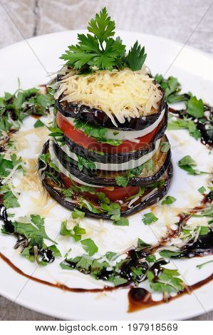 Appetizer from eggplant slices of mozzarella combined in a pile with tomatoes spilled with herbs seasoned Parmesan cheese