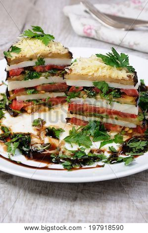 Appetizer from eggplant slices of mozzarella combined in a pile with tomatoes spilled with herbs seasoned Parmesan cheese. In section