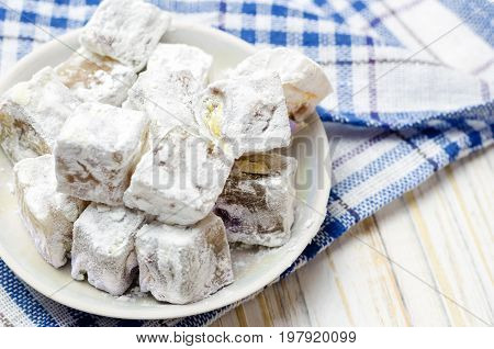 Turkish delight with pistachios on white wooden background.