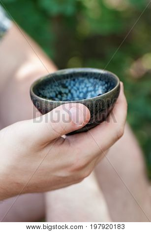 Tea bowl in men's hand closeup. Tea ceremony outdoors.