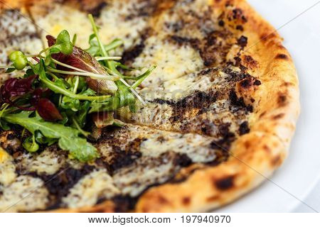 Pizza with truffles, ruccola and cheese on the white table cloth