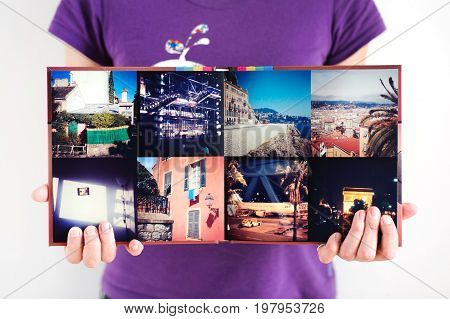 Opened square travel photo album in woman hands background