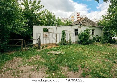 Old ruined white house on the background of new modern building