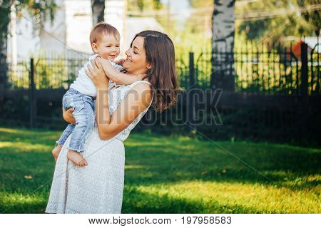 Young beautiful mother holding her little baby on the hands and whirling