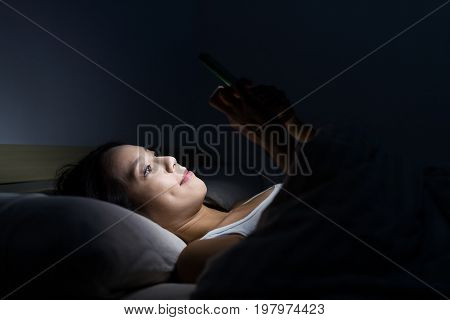 Woman using mobile phone and lying on bed