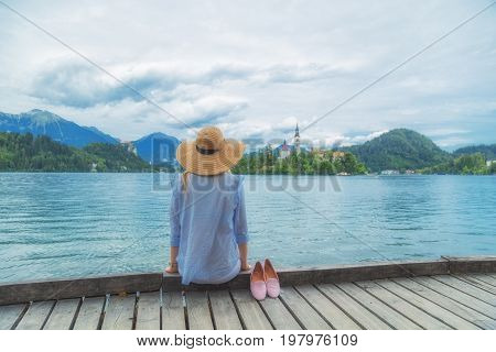 Young woman sitting on a wooden pier and enjoying the summertime.